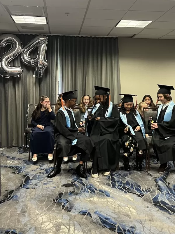 Children sitting in graduation gowns