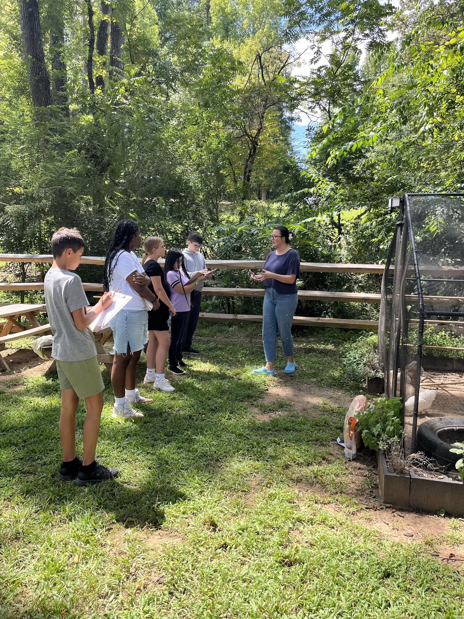Guide talking to 5 adolescent students in front of a chicken coop