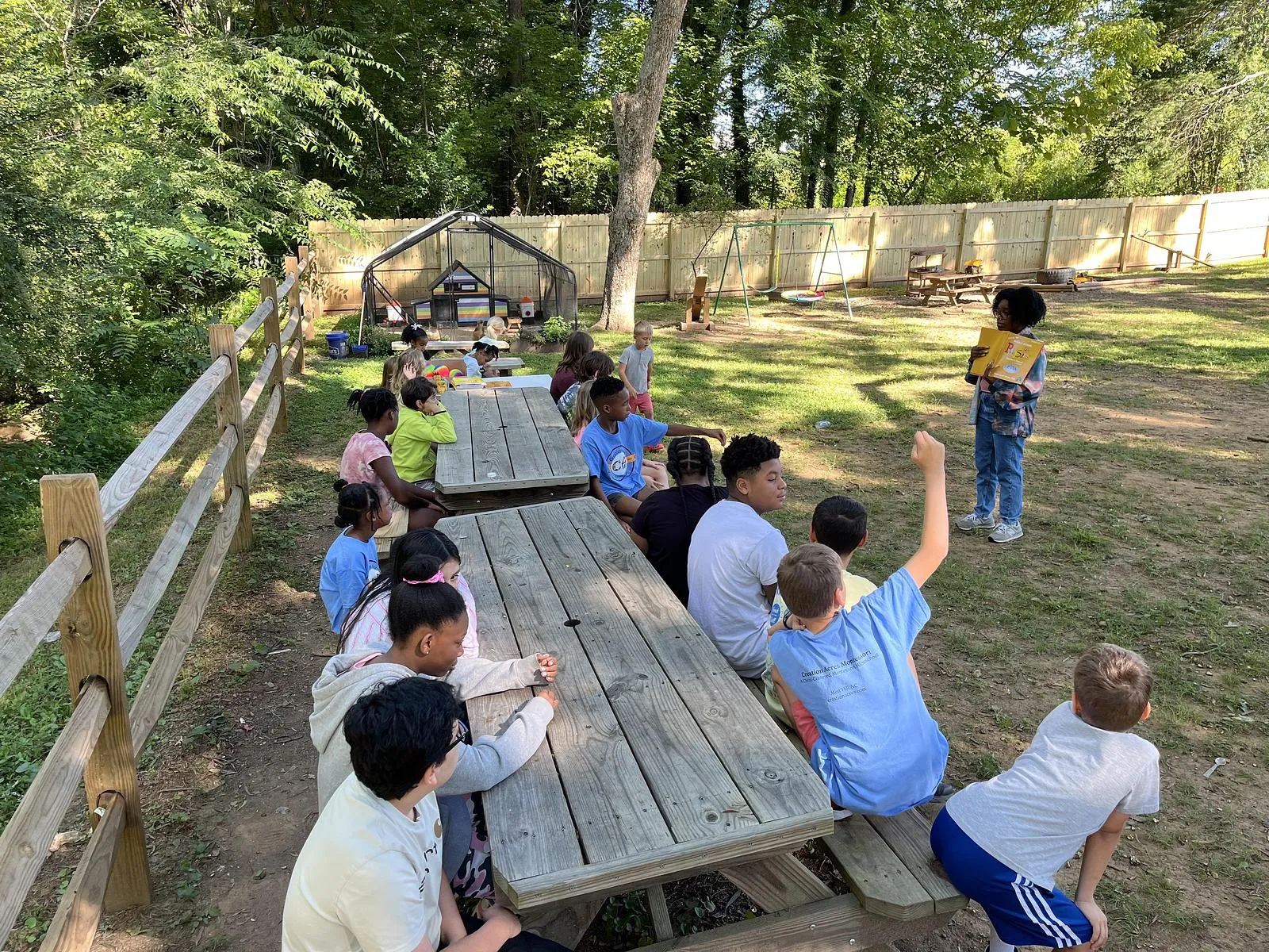 A teacher reading to a group of children outside